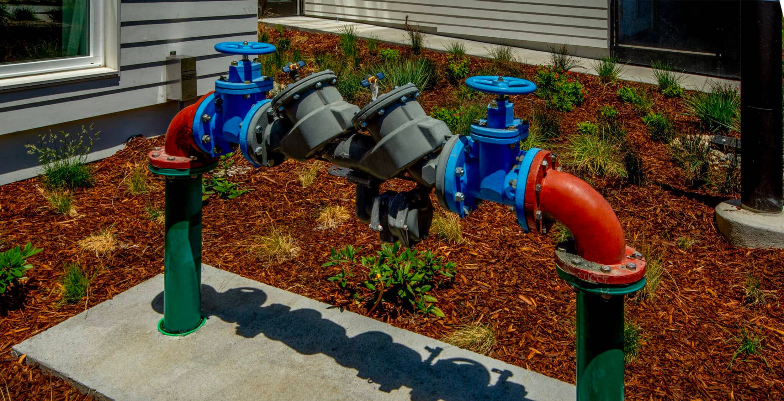 Row of backflow assemblies installed along landscape